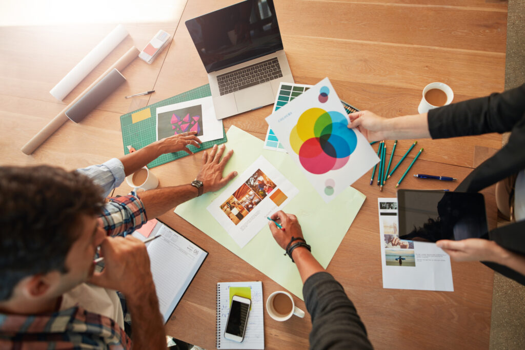 Equipo creativo desarrollando elementos de branding e identidad visual para emprendedores y empresas, con análisis de paletas de colores, tipografías y recursos gráficos sobre una mesa de trabajo.